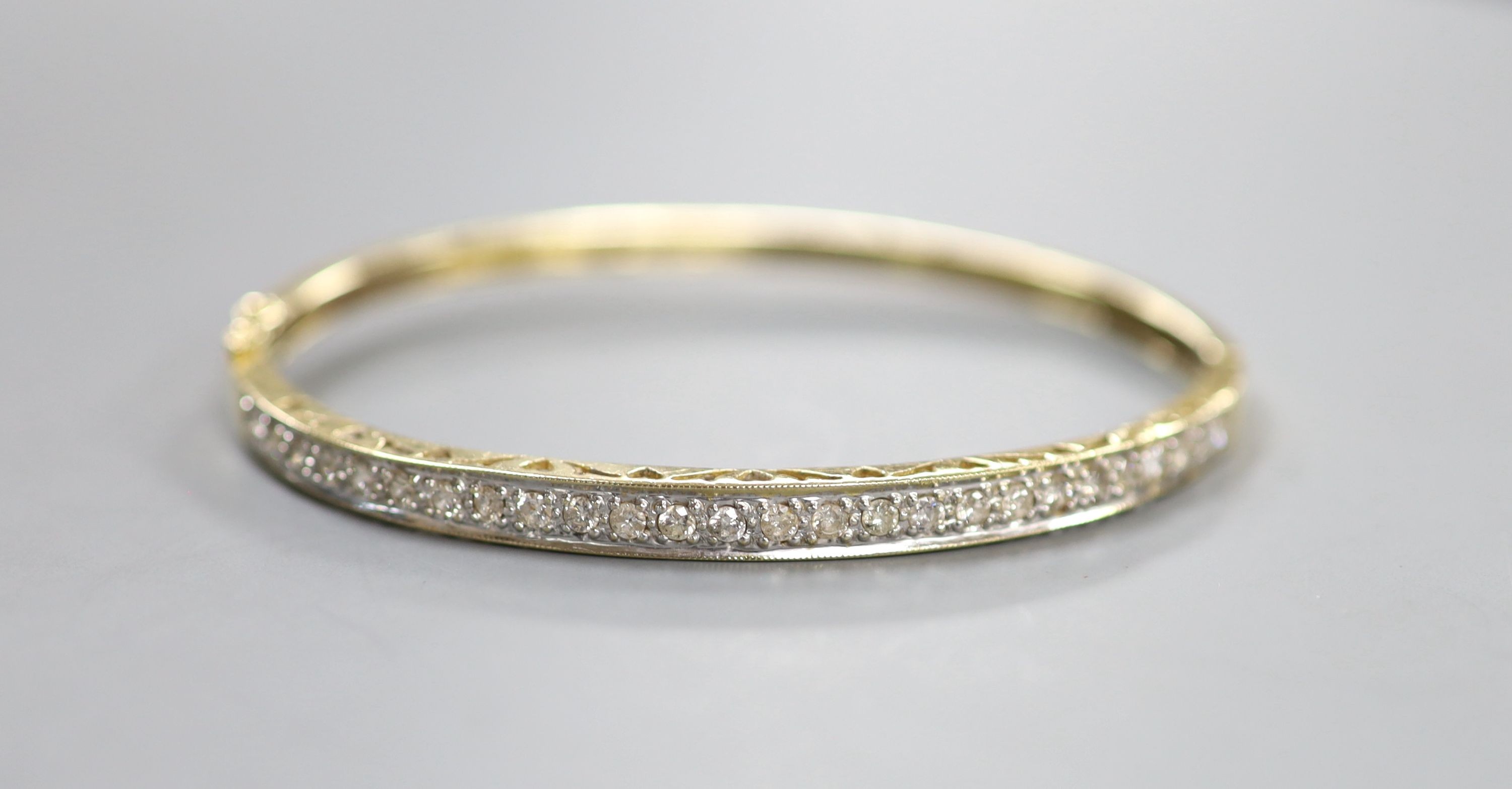 A modern 585 yellow metal and diamond chip set hinged bangle, interior diameter 62mm